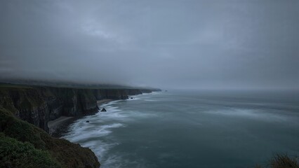 Cliffs and coastline under a cloudy sky, with the sea crashing against the rocks. Nature and landscape scene. Weather and ocean. The image of cliffs and ocean under stormy weather.
