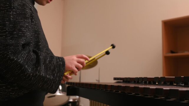 A girl plays the xylophone, close-up of her hand and hits the keys with sticks.
