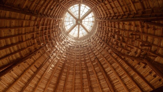 Inside view of a wooden dome with a circular window at the top. Architectural structure and design. Interior of a building.