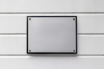 Blank metallic sign on white paneled wall