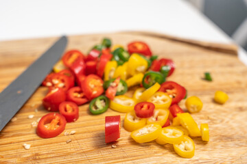 Close-up of sliced chili peppers with seeds on a wooden cutting board. Bright colors highlight spice and freshness.