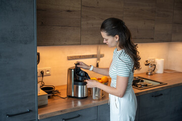 A woman assembles a juicer on a kitchen counter at home. Real life interior scene showing everyday food preparation, healthy routine and domestic organization.