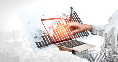 A business professional interacts with digital graphs and charts on a laptop in an urban setting, symbolizing data analysis and strategic growth. Impute