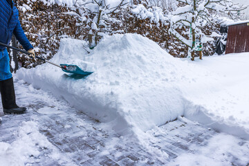 Close up view of person shoveling snow from paved walkway in front of villa entrance during winter. Sweden.