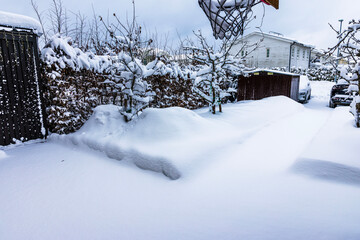 View of snow covered residential yard with parking area and cars before snow removal during winter. Sweden.