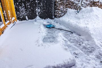 Close up view of snow shovel on snow covered villa walkway before snow removal during winter. Sweden.
