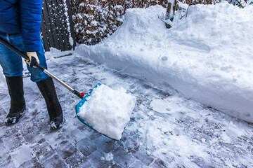 Close up view of person removing snow with snow shovel on icy walkway during winter. Sweden.