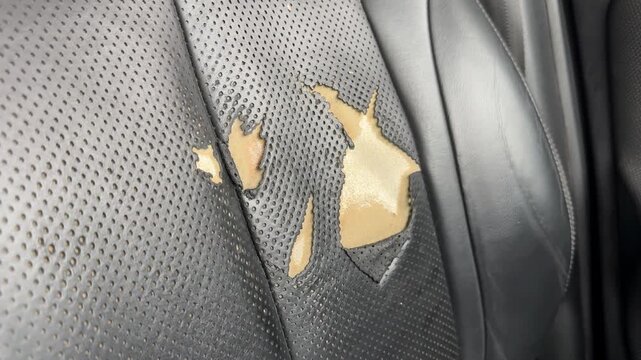Worn black car seat upholstery with visible tears as automotive background
