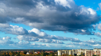 Blue sky with fluffy clouds lined up in a row and high-rise buildings in the background