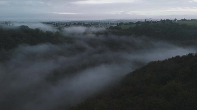 Aerial of hills and forest countryside in the fog