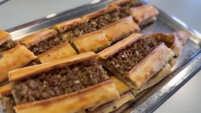 Turkish pide with minced meat filling on metal tray, popular Middle Eastern dish
