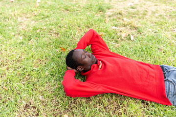 African man relaxing on grass, enjoying peaceful moments outdoors in a park