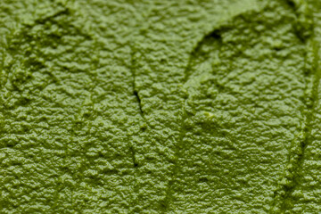 Close-up view of pesto-like spread made of arugula greens, walnuts, parmesan, garlic, and olive oil.  Texture of green vegetarian spread.