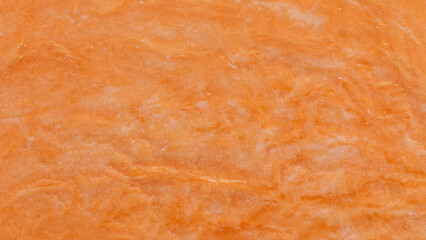 Orange wallpaper. Close-up view of the surface of a halved raw sweet potato.