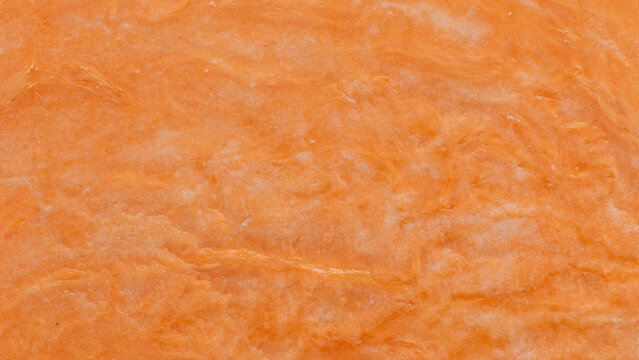 Orange wallpaper. Close-up view of the surface of a halved raw sweet potato.