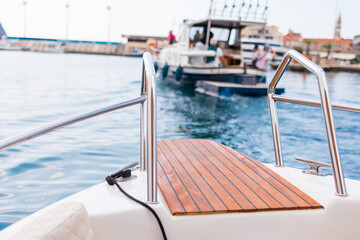 Obraz premium Motorboats sailing into harbor near coastal town. Seaside tourism, recreational boating and marine lifestyle in summer.