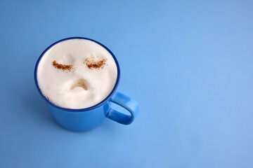 Blue monday concept. Sad face cappuccino resting on a blue background
