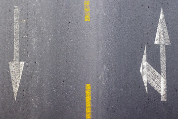 Road arrows marked on asphalt with yellow divider line