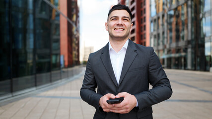 Man stands outside buildings while using smartphone
