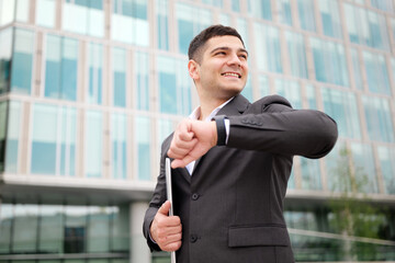 Businessman checks watch in front of office building