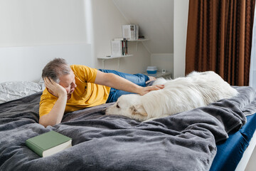 Man relaxing on bed stroking pet dog