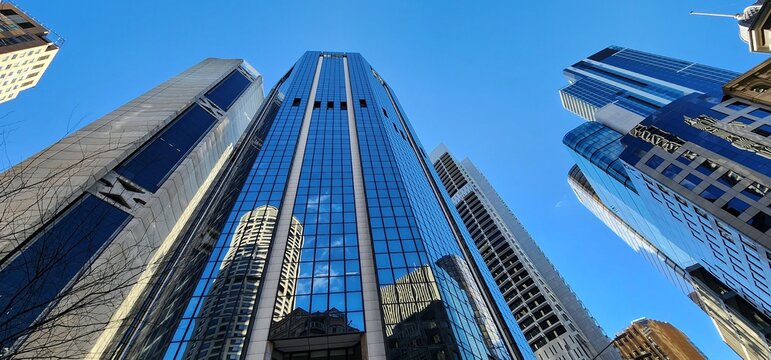 Sydney, Australia - 30 July 2023: Sydney CBD Architecture &ndash; Upward View of Modern Skyscrapers with Reflective Glass Facades. The photo illustrates a dramatic upward view of several modern skyscrapers.