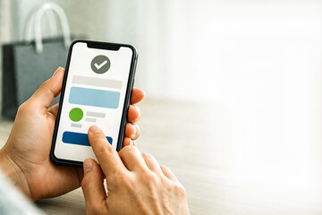 Hands holding smartphone with green checkmark on screen, successful mobile payment or verification concept