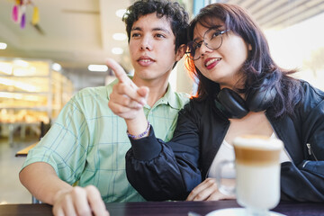Young couple on date pointing at cafe