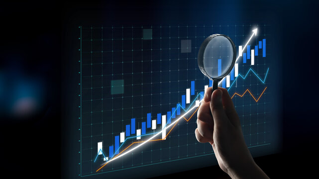A hand holding a magnifying glass examines a detailed stock market chart, emphasizing growth trends and financial insights in a digital format. Impute - Powered by Adobe