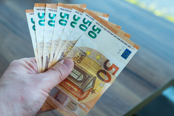 Close up hand holding a fanned out stack of fifty euro bills