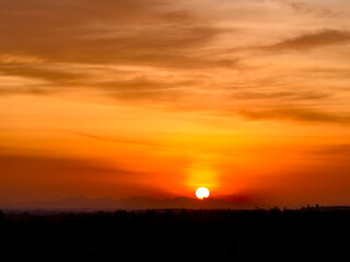 The sun sets dramatically, casting an orange glow across the sky
