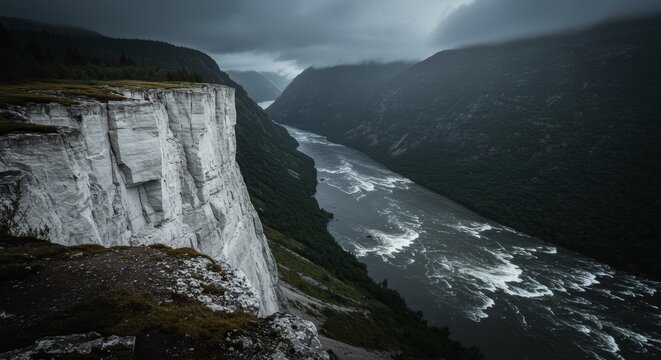 Majestic river flowing through a dark mountain valley with a dramatic white cliff on one side, capturing the raw power of nature.