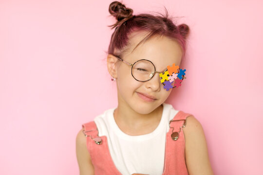 A child with an autism symbol on his glasses winks at the camera. Support for children with autism spectrum disorder.