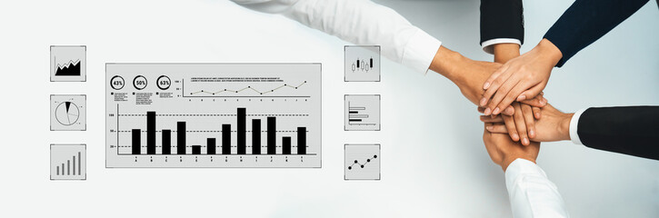 Diverse professionals join hands in collaboration over data charts, symbolizing teamwork and success in achieving financial goals within the corporate environment. Trope