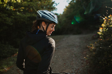 Portrait of a sporty girl with her bike in the forest, wearing a safety helmet