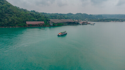 Fototapeta premium Verdant Voyage: Lone Ferry Crossing Jade Waters In Guimaras, Philippines