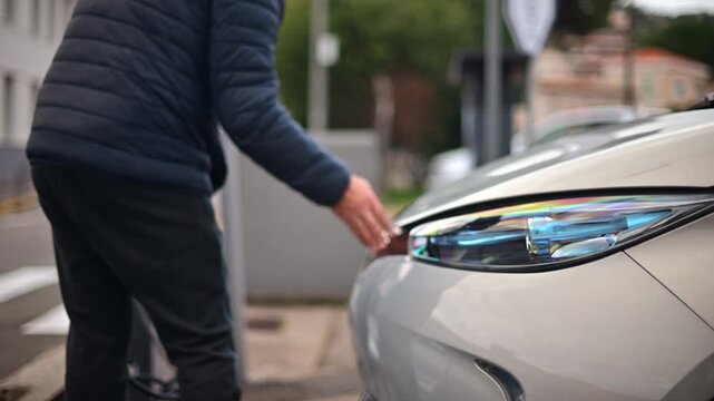 Man unplugging an electric car from a public charging station