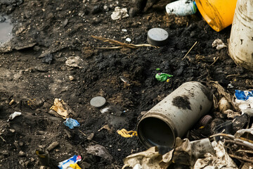 Close up of polluted soil with hazardous waste plastic and trash symbolizing environmental contamination and human impact