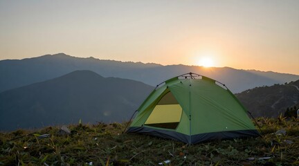 Camping tent glows against a backdrop of mountains and sunrise on a grassy hill
