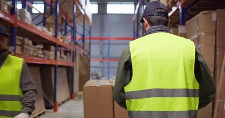Warehouse workers move boxes on pallet jack. Shelves and racks define an efficient logistics aisle. Safety vests and gloves show teamwork. Clear warehouse teamwork logistics concept. - Powered by Adobe
