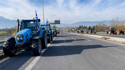 Naklejka premium Blue tractors on rural highway demonstration with greek flags on sunny day.