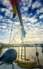 A stunning view from a sailboat with vibrant clouds and shimmering water reflecting the warm evening light