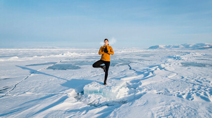 Woman practicing yoga balance pose on ice floe in frozen landscape