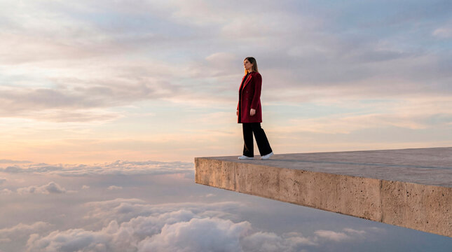 Woman standing on a concrete platform above the clouds