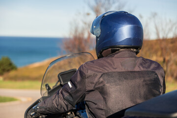 Elderly man riding motorcycle by sea on road trip