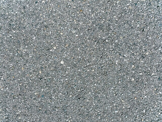 A gray sidewalk surface made of concrete with visible small stones and a rough texture seen outdoors even lighting and a typical urban look without any visible cracks