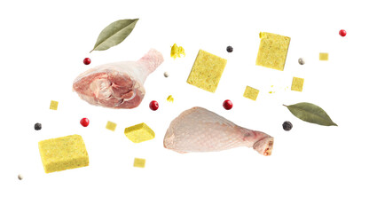Bouillon cubes, chicken drumsticks, dry bay leaves and peppercorns flying in air on white background