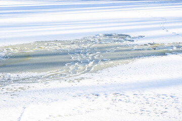Melted ice on a frozen river. Blue shadows on white snow. Background
