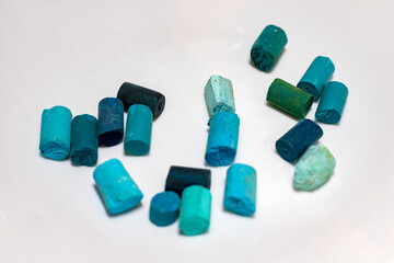 Dry pastel on a white background. Pieces of broken teal dry pastel, art supplies for painting and drawing.