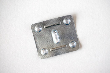 Empty metal used blister pack for one tablet, isolated on white background. Metal capsule blister top view.